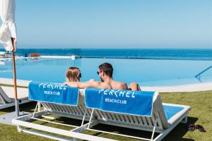 Ein Mann und eine Frau sitzen auf Stühlen neben einem Pool in der Unterkunft Resort Cordial Santa Águeda & Perchel Beach Club in La Playa de Arguineguín