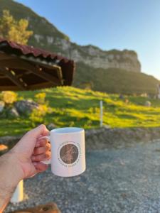 a person holding a coffee cup in front of a field at Refúgio Serra da Tartaruga - Alfredo Wagner in Alfredo Wagner