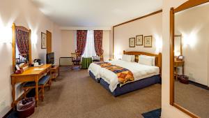 白河African Sky Hotels - Pine Lake Inn的一间配有床、书桌和桌子的酒店房间 更多37张照片