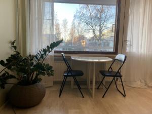 - une table et deux chaises dans une chambre avec fenêtre dans l'établissement Kaunis yksiö, 600m keskustaan, ilm parkit, à Oulu