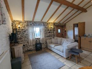 a living room with a couch and a stone wall at Elegant and secluded 1-Bed Cottage near Bideford in Bideford