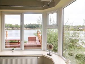 a room with three windows and a view of the water at Lakeside 12 in Carnforth
