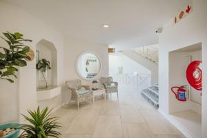 a white hallway with chairs and a table and stairs at Bayview Hotel in Plettenberg Bay