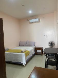 a small bedroom with a bed and a table at Kellocks' Seaview Apartelle in Dalaguete
