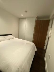 サットンにある2 BR Flat in Sutton London NH70のベッドルーム1室(白いベッド1台、スライドドア付)