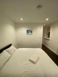 uma cama branca com uma toalha branca em 2 BR Flat in Sutton London NH70 em Sutton