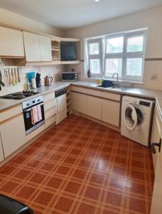 a kitchen with white cabinets and a washer and dryer at Ness City Apartment in South Kessock