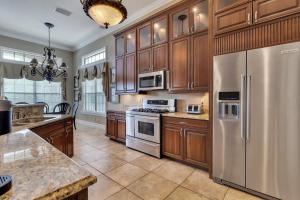 una cocina con armarios de madera y electrodomésticos de acero inoxidable en Luxury 5 bed 5.5 bath Villa close to everything, en Kissimmee