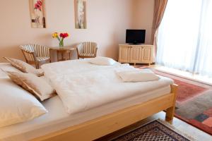 a large bed in a room with chairs and a television at Hotel Karpatsky Dvor Lozorno in Lozorno