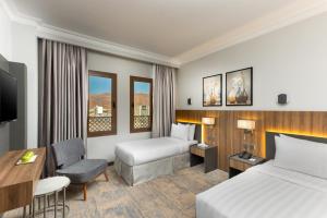 um quarto de hotel com duas camas e uma secretária em Ewan Dar Alhejra Hotel em Medina