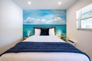 The Lauderdale Boutique Hotel في فورت لاودردال: غرفة نوم بسرير مع لوحة للمحيط