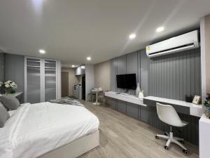um quarto com uma cama, uma secretária e uma televisão em Sweet room in Nimnan em Chiang Mai