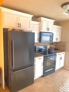 a kitchen with a stainless steel refrigerator and white cabinets at Cheerful 3 Bdrm space, 2 bath!. You gotta love it! in Oklahoma City