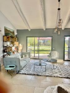 een woonkamer met een bank en 2 tafels bij Villa avec Pool House au cœur des vignes - Lubéron in La Tour-dʼAigues