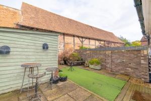 a garden with two stools next to a building at 2 BR Stylish Bright Cottage, Pet Friendly - Titchfield Village by Blue Puffin Stays in Titchfield