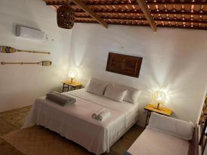 a bedroom with a white bed and two lamps at Casa Ana Frank in Parajuru