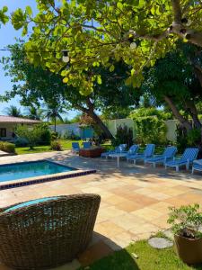 a swimming pool with blue lounge chairs and a tree at Casa Ana Frank in Parajuru