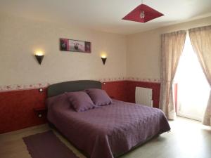 a bedroom with a bed with a purple blanket at LES COTEAUX DE VIGNY 