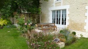 a wooden bench sitting in a garden next to a window at LES COTEAUX DE VIGNY 