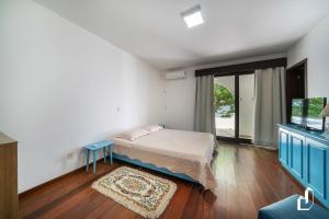 een kleine slaapkamer met een bed en een televisie bij Apartamento com a vista para o melhor pôr-do-sol da cidade in Bombinhas