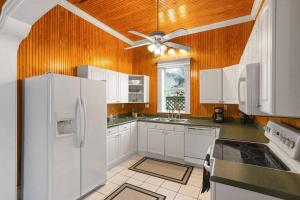 a kitchen with white appliances and a ceiling fan at The Bays Best Bungalow in Tampa