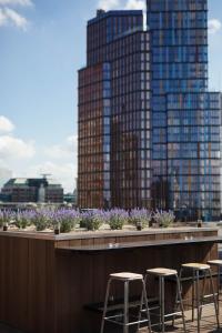 a row of stools on a rooftop with tall buildings at Montcalm Royal London House, London City in London