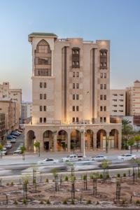 un grand bâtiment avec des voitures garées dans un parking dans l'établissement Ewan Dar Alhejra Hotel, à Médine
