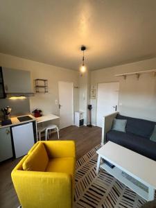 een woonkamer met een gele bank en een keuken bij Appart du Théâtre in Caen