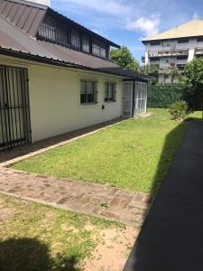 a house with a grassy yard next to a building at Casa Tipo Loft- Tigre Centro Con Jardin, Parrilla Y Pileta de Lona Grande 4 Personas in Tigre