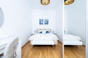 een witte slaapkamer met een bed en een stoel bij OrestaLiving - Spacious 2BR on the Danube Canal in Wenen