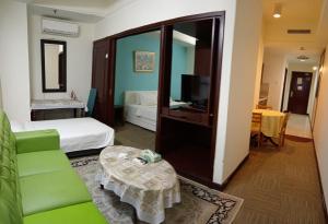 a hotel room with a green couch and a television at Crown Apartment at Times Square in Kuala Lumpur