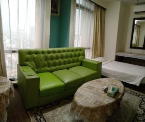 a green couch in a room with a bed and a table at Crown Apartment at Times Square in Kuala Lumpur