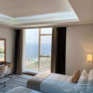 a hotel room with a bed and a large window at Seafront Luxury Suites Jeddah Corniche in Jeddah
