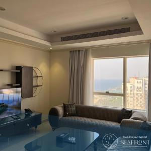 a living room with a couch and a large window at Seafront Luxury Suites Jeddah Corniche in Jeddah