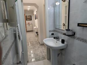 ein weißes Badezimmer mit einem Waschbecken und einem Spiegel in der Unterkunft GevyNapule in Neapel