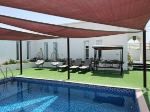 a swimming pool with chairs and a large umbrella at Labella Chalet in Barka