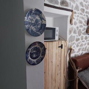 Zwei Teller hängen an einer Wand neben einer Mikrowelle. in der Unterkunft Σαν Παραμυθάκι in Filýra