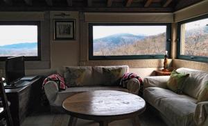 sala de estar con sofá, mesa y 2 ventanas en Apartamento Rural El Herrero vistas espectaculares a Gredos, en Cabezas Bajas