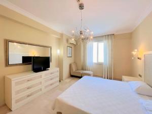 a bedroom with a white bed and a flat screen tv at Gold City 5 star resort 2+1 appartement sea view and aqua park in Alanya
