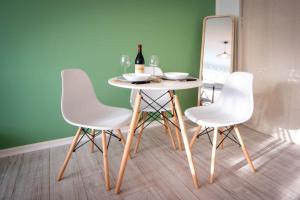 einen Tisch mit 3 weißen Stühlen und einem Spiegel in der Unterkunft Le studio tropical in Chalon-sur-Saône