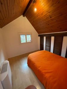 a bedroom with an orange bed in a attic at Maison de campagne avec piscine in Courbouzon
