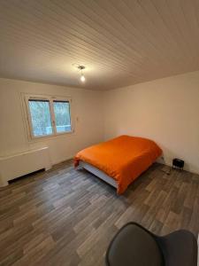 ein Schlafzimmer mit einem orangenen Bett in einem Zimmer in der Unterkunft Maison de campagne avec piscine in Courbouzon