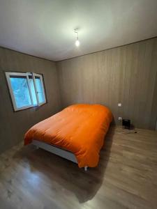 a bedroom with a bed with an orange blanket at Maison de campagne avec piscine in Courbouzon