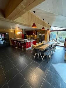 uma grande cozinha com uma mesa e cadeiras em Maison de campagne avec piscine em Courbouzon