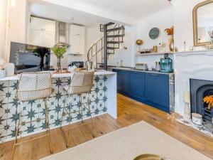 a kitchen with blue cabinets and a fireplace at The Railway Cottage - Stylish & Dreamy Home in the Heart of Whitstable in Kent
