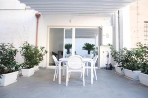 ein weißer Tisch und Stühle auf einer Terrasse mit Topfpflanzen in der Unterkunft Arabesque Luxury Apartment - Roof Garden in Taranto