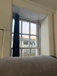 a bedroom with a bed and a large window at Bath Backpackers in Bath