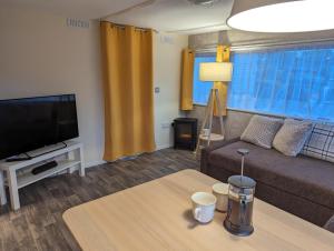 a living room with a couch and a tv and a table at The Piggery in Witheridge