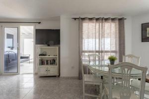 una sala da pranzo con tavolo, sedie e TV di Corralejo Beachfront Villa Remos with Lobos Island View, Private Pool, Wifi & BBQ by Amazzzing Travel a Corralejo