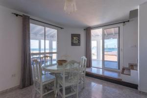 a dining room with a table and chairs with a view of the ocean at Corralejo Beachfront Villa Remos with Lobos Island View, Private Pool, Wifi & BBQ by Amazzzing Travel in Corralejo